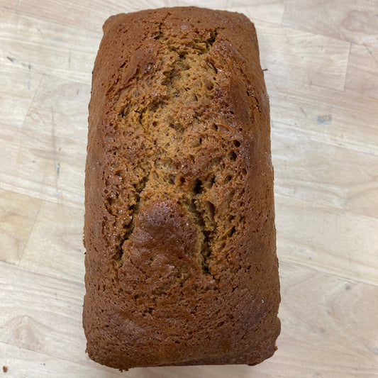 Loaf of brown honey cake on a light wooden surface